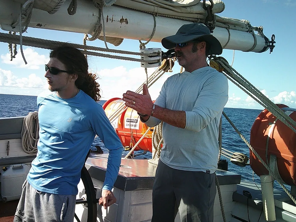 two people stand on a ship near the masts and rigging