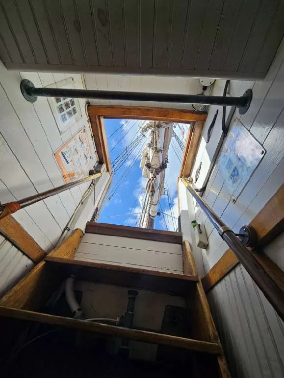 looking up a ladder at sail rigging and blue sky