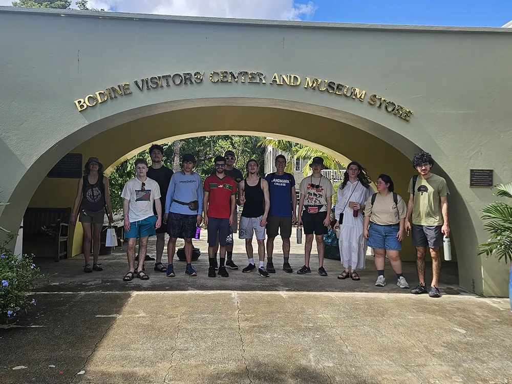 Students lined up under an archway with lettering that reads Bodine Visitors Center and Museum Store