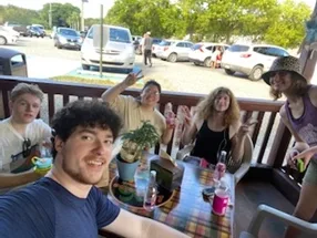 Five students gathered around a table on an outdoor restaurant patio