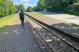 people walking away from the camera, along empty railroad tracks.