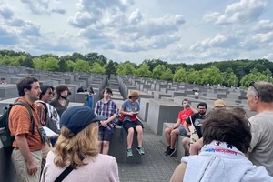 group of students sitting on stone pillars with stone pillars extending into the background