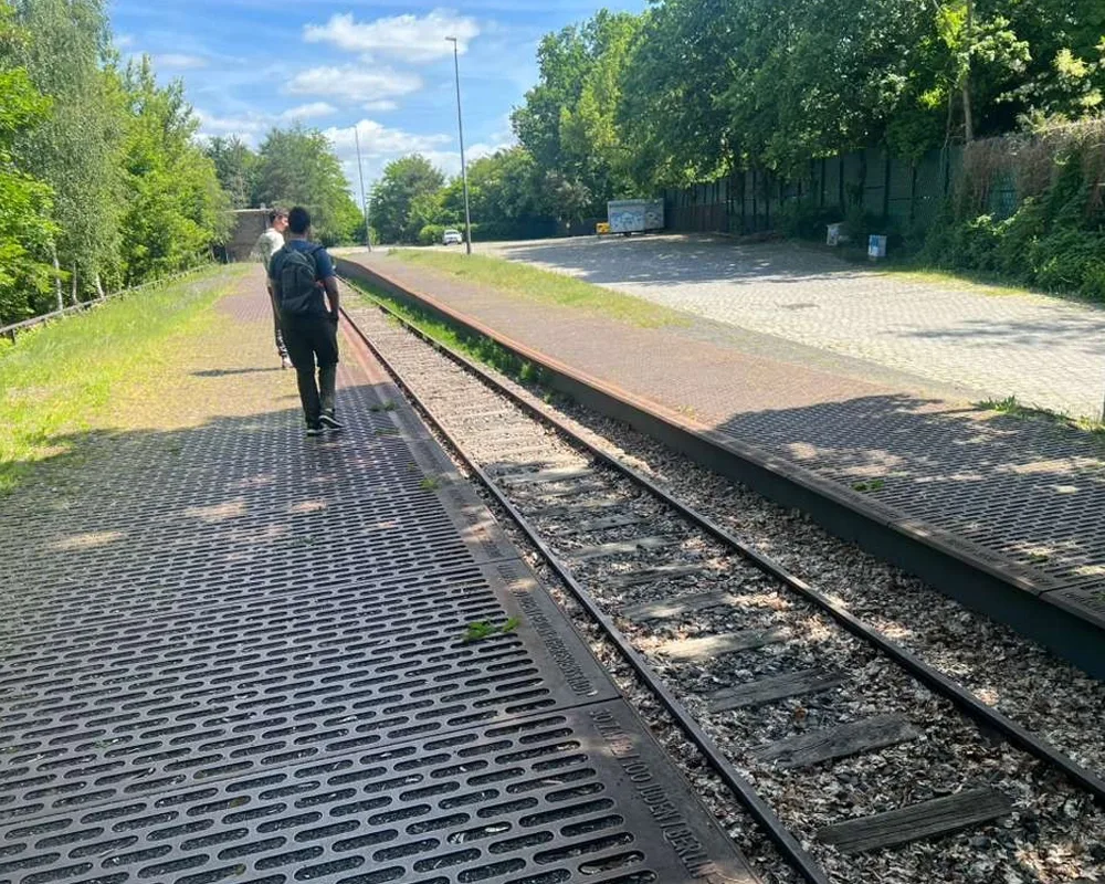 picture of people walking away from the camera, along empty railroad tracks.