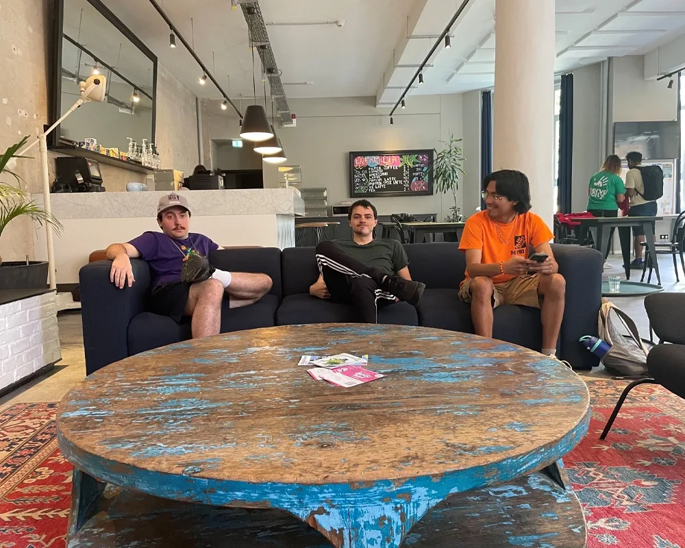 students sitting on couches with a large round coffee table.