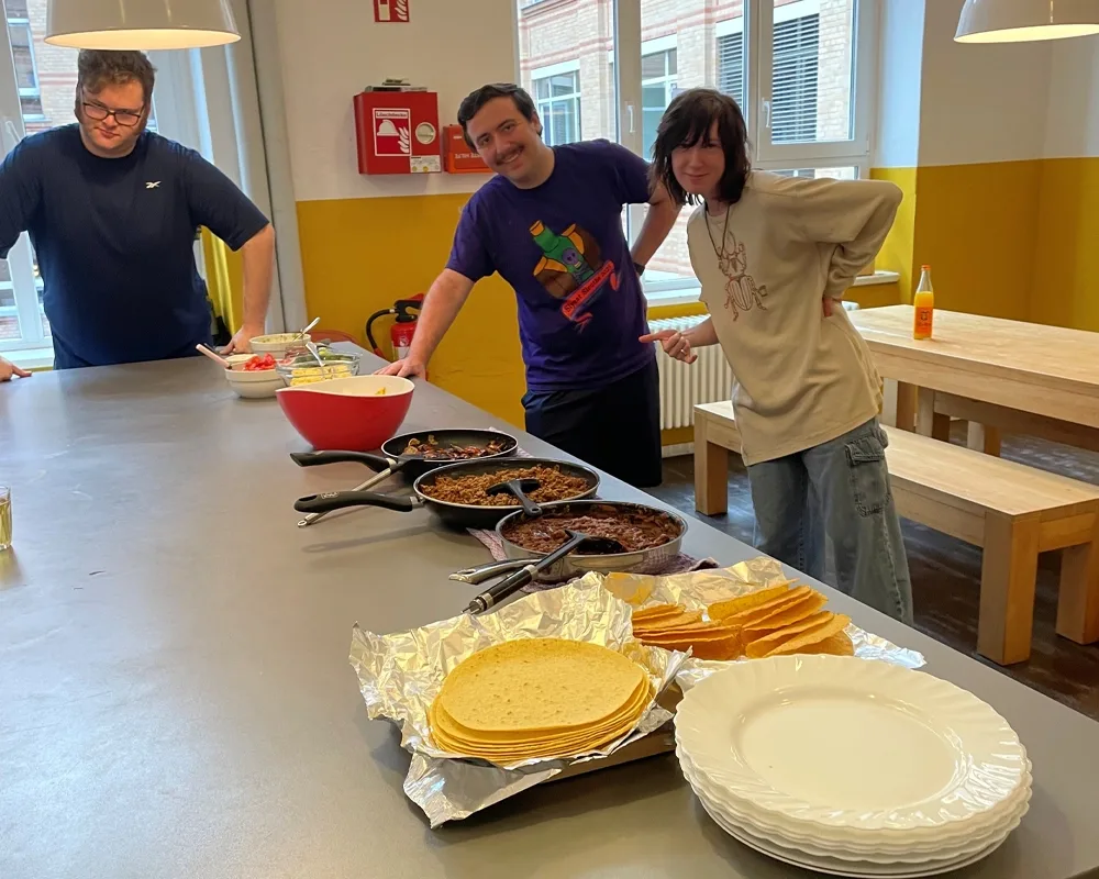 three people at a kitchen counter with a buffet spread out in front of them.