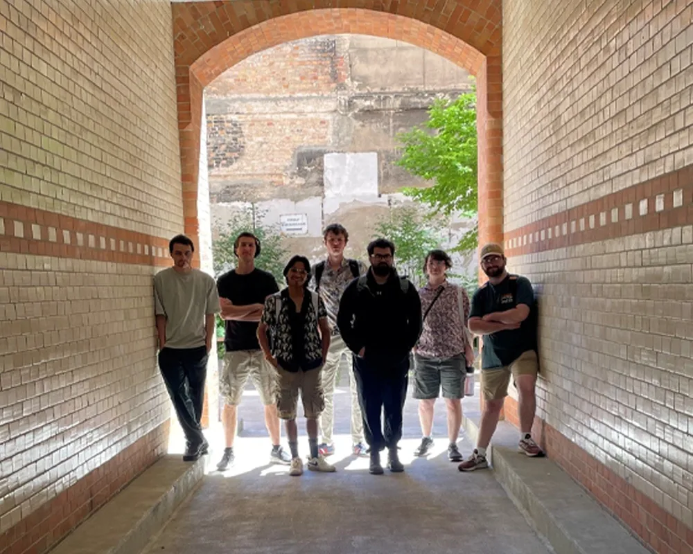 A group of students standing in an arched entrance to a courtyard.