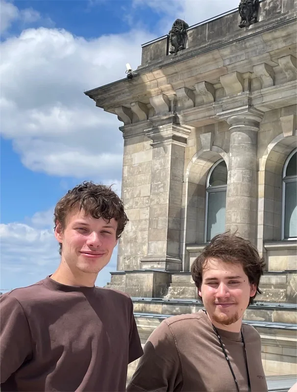 close up of two students with a view of a tower and the city behind them.
