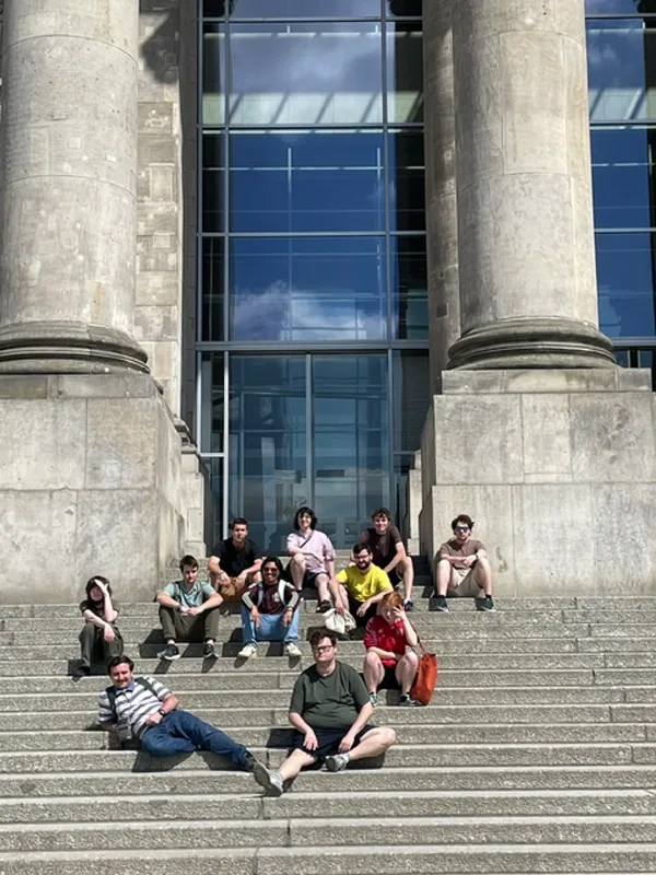 group of students sitting on the stone steps of the German Reichstag.