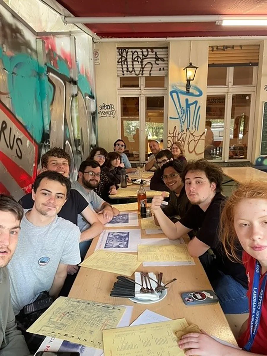 Long table with a group sitting around it looking at the camera.