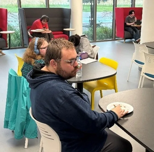 Students sitting at tables eating pizza before getting down to writing