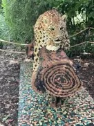 A life sized Lego leopard crouched on a Lego log