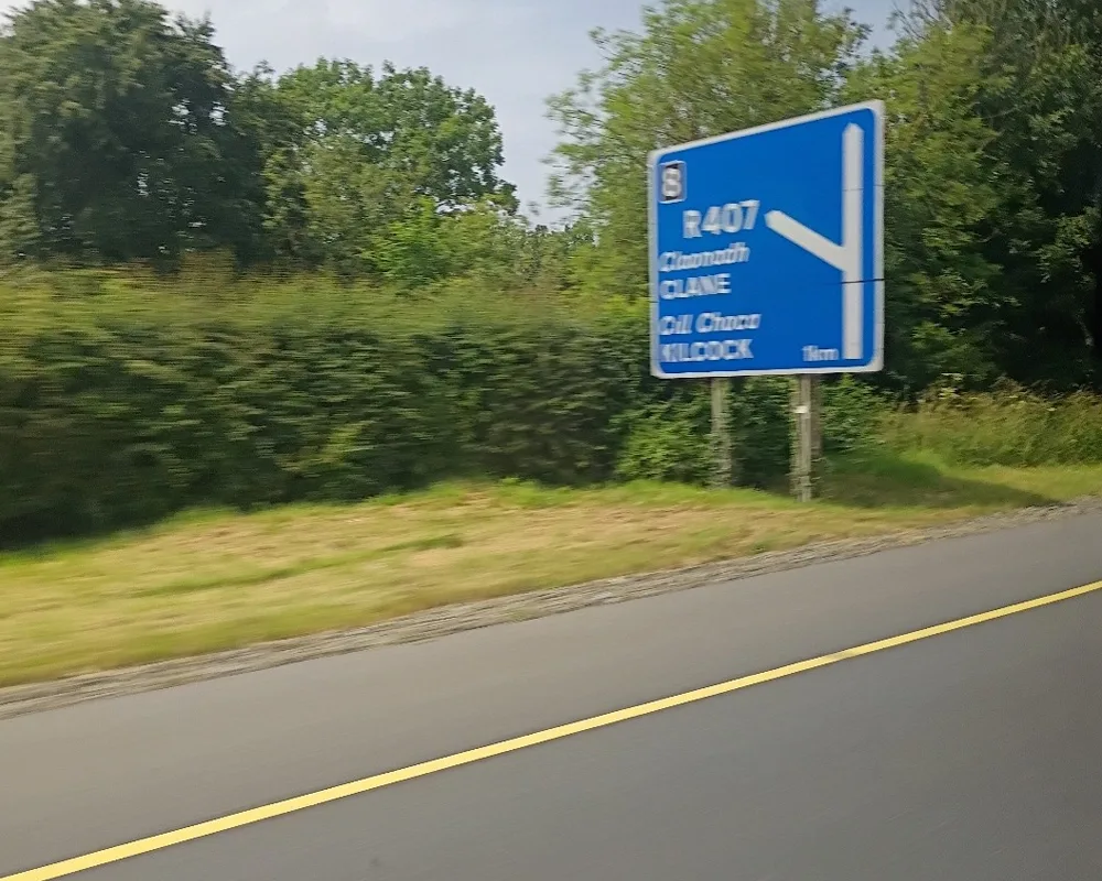 Photo of highway sign indicating the R407 exit to Clane and Kilcock with the place names in English and Irish