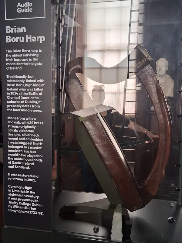 Harp encased in glass with a placard explaining its history