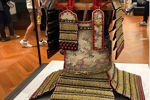 A replica of an ancient samurai helmet in a glass case at a museum.
