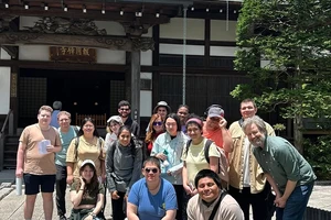 A group of students and group leaders pose for a photo in front of a temple.