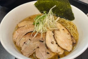A bowl of ramen (Japanese noodle soup) with meat, broth, and vegetables.