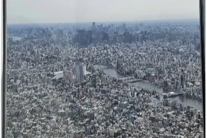 A view of the city of Tokyo from high above. Dense urban buildings and a river are seen.