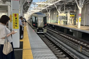 A train enters an above-ground, outdoor station in Tokyo, Japan.