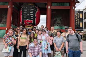 A group of students standing in front of a gate and large lantern.