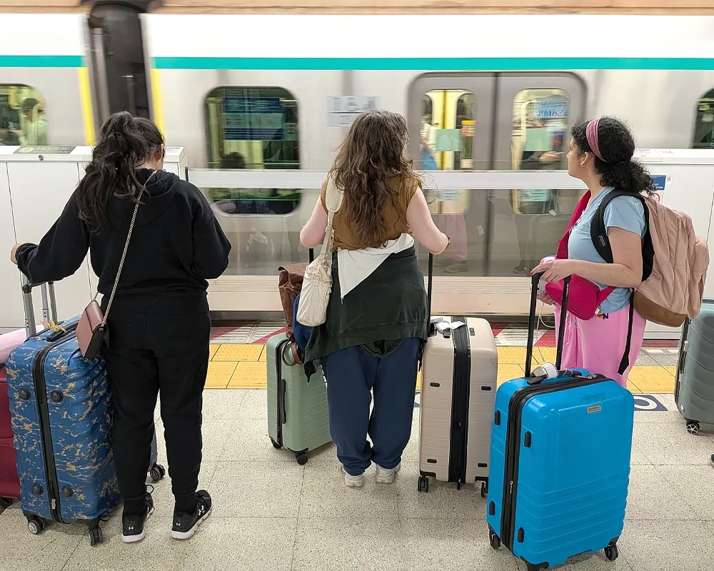Three students await a subway train.