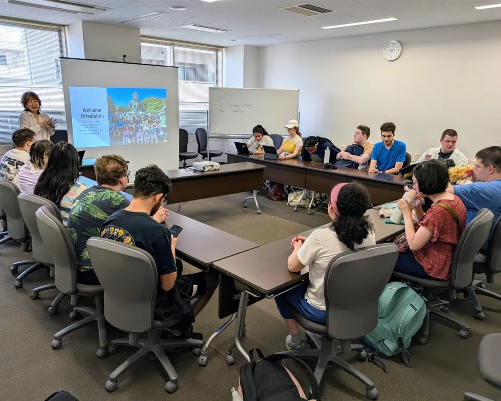 A teacher stands at the front of a classroom full of students.
