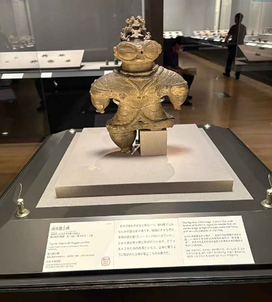 An ancient artifact made of clay in a glass case at a museum.