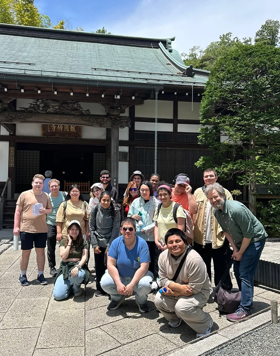 A group of students and group leaders pose for a photo in front of a temple.