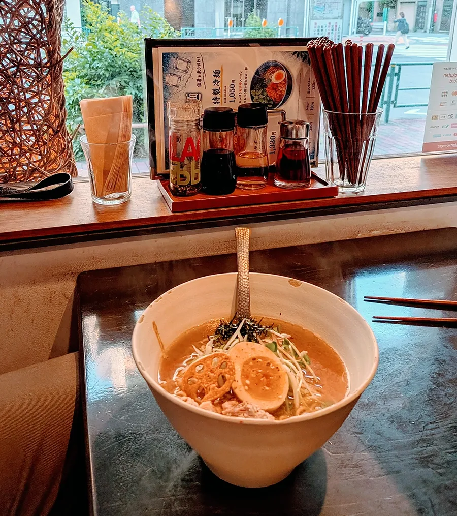 A bowl of ramen (Japanese noodle soup) with meat, broth, vegetables, and egg.