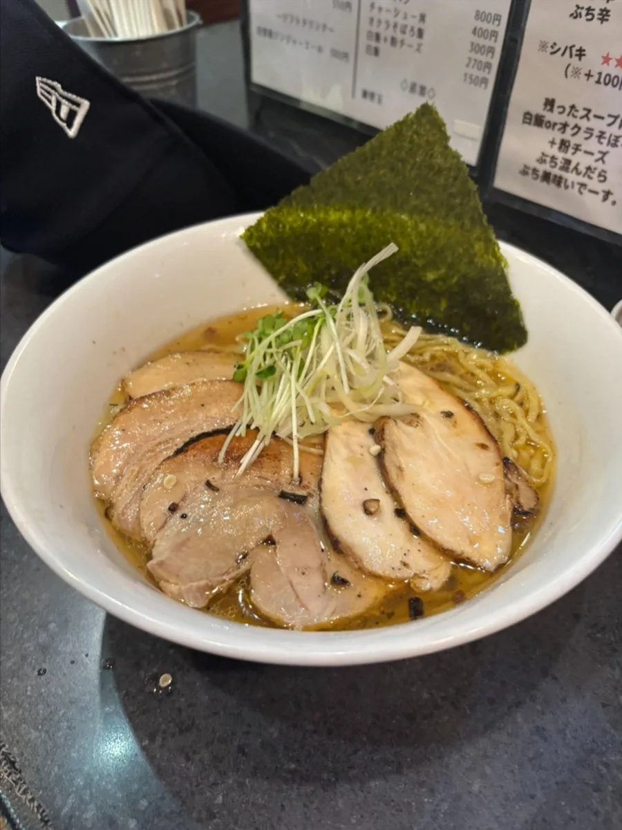 A bowl of ramen (Japanese noodle soup) with meat, broth, and vegetables.