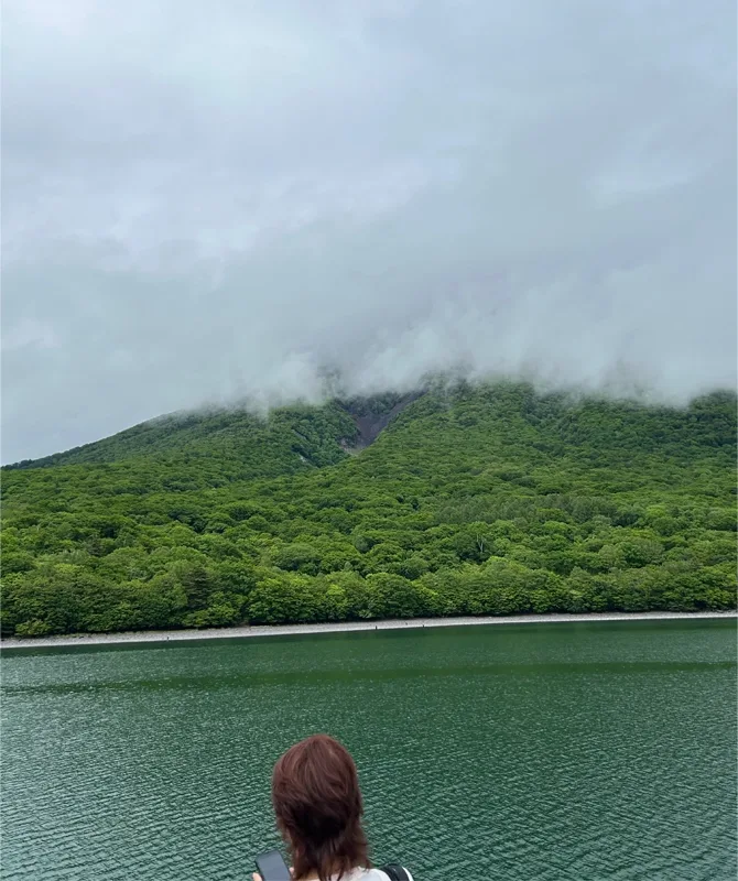 Clouds, hills, a lake, and a person looking out.