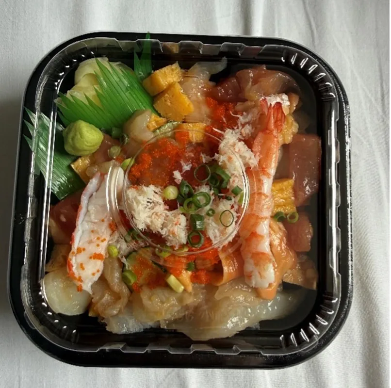 A plastic container full of sushi, mainly shrimp and fish.