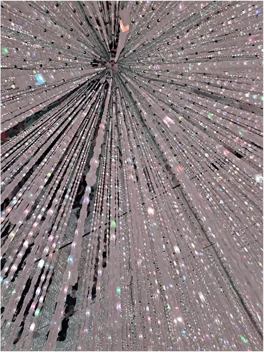 Looking up at crystal-like lights hanging from the ceiling, reflected in mirrors on the walls and ceiling