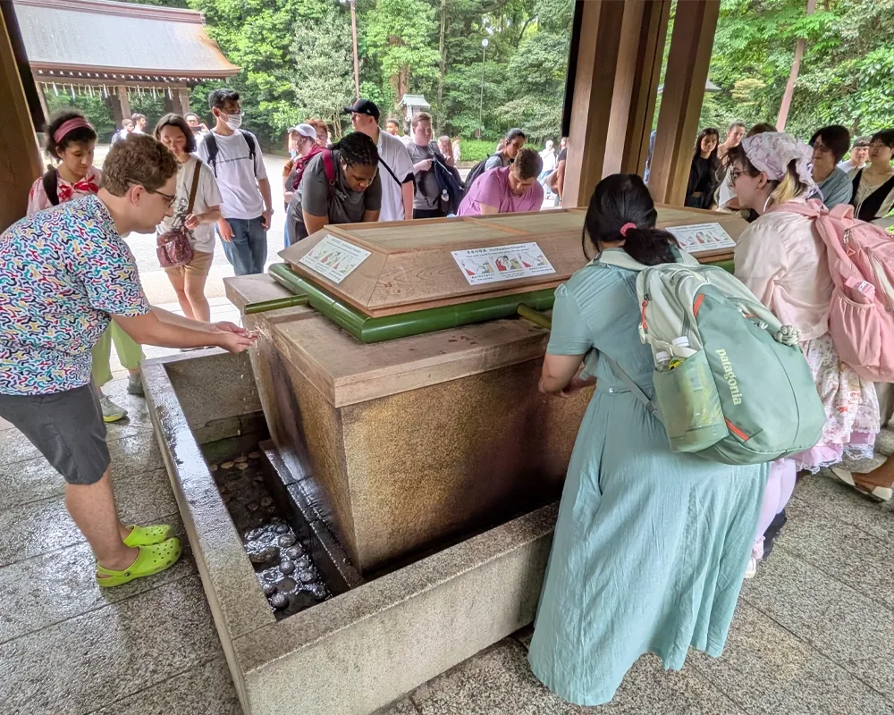 Students gather around a fountain to rinse their hands and mouths before entering a shrine.