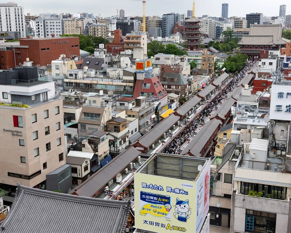 A view of a busy city shopping street and Buddhist temple as seen from a high vantage point.