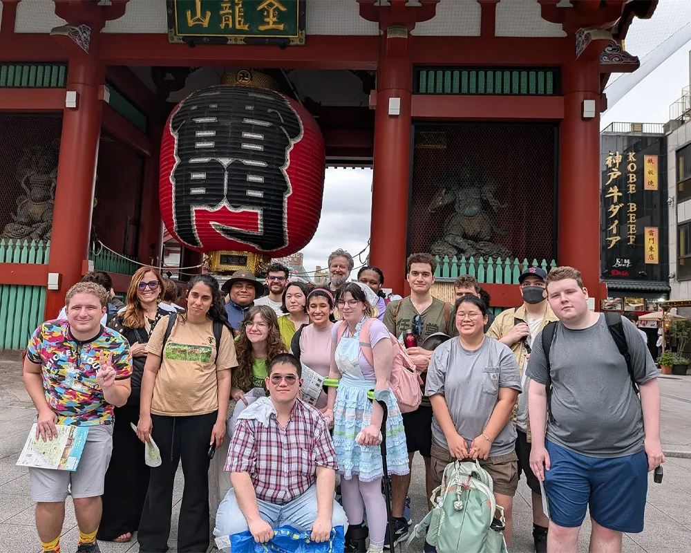 A group of students standing in front of a gate and large lantern.