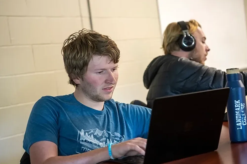 A student in a blue shirt looking at his laptop screen.
