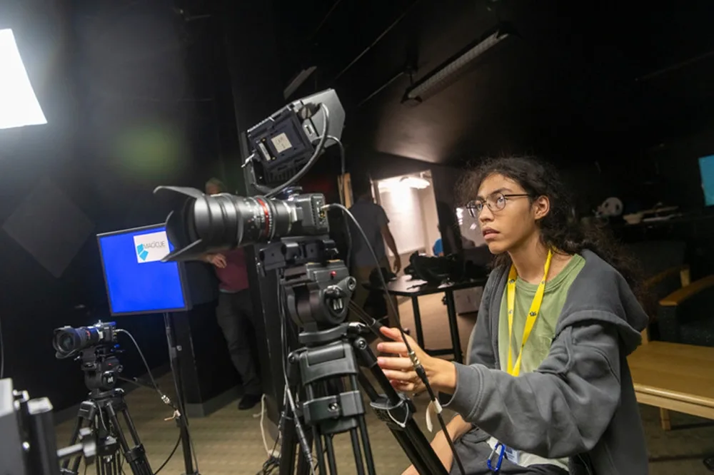A student operating a camera in the video production lab.