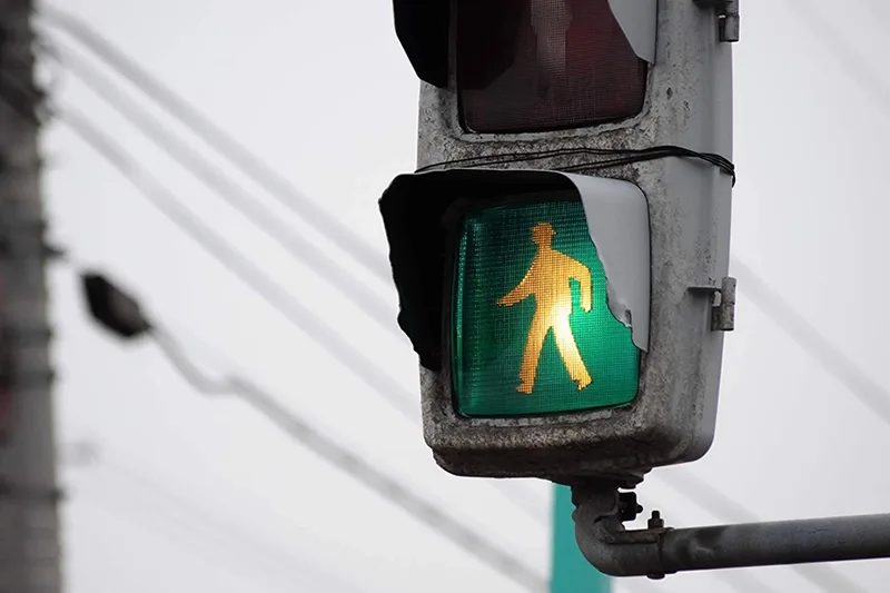 A figure of a person on a green illuminated walk sign indicating to cross the street.