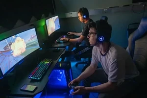Gamers competing on computer screens in a dimly lit room.