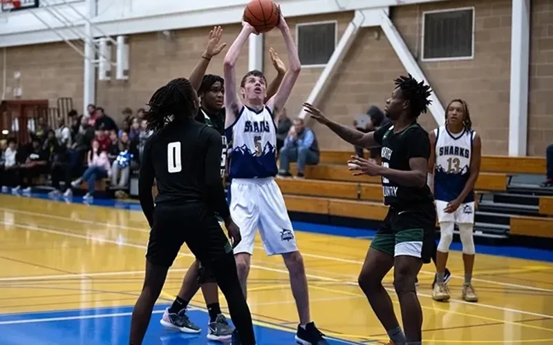 LC men's basketball player making a shot at the hoop with defense surrounding him.