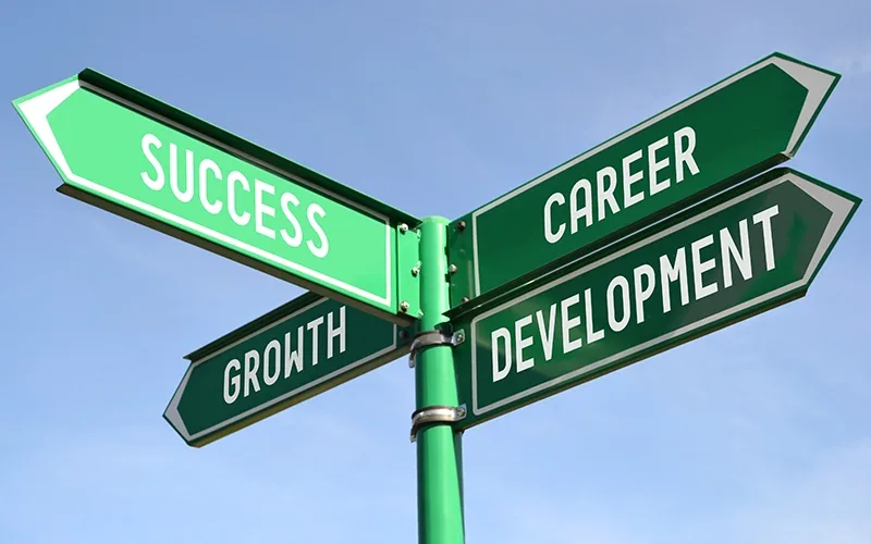 A green road sign showing the words success, growth and career development.