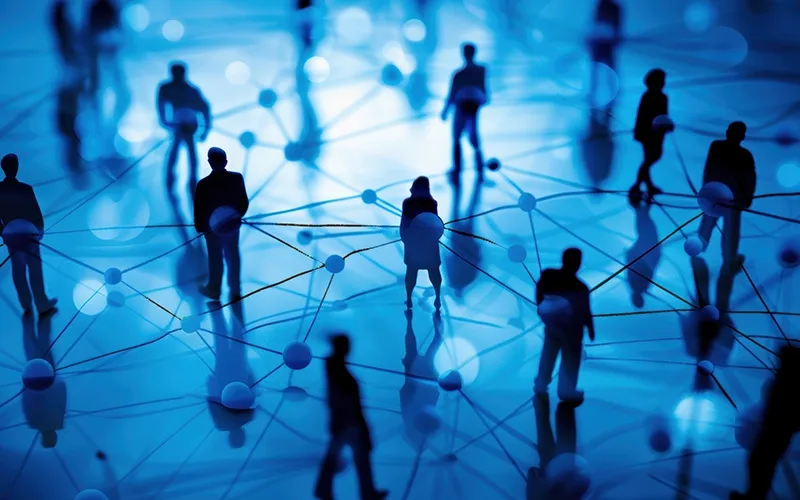 Silhouettes of business people and dots in a network.