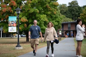 Two smiling parents walking across the quad on family weekend.
