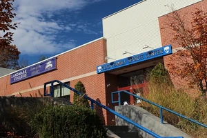 A photo of the Click Family Sports Center, a brick building bearing its name and a banner that says "Landmark College Home of the Sharks."