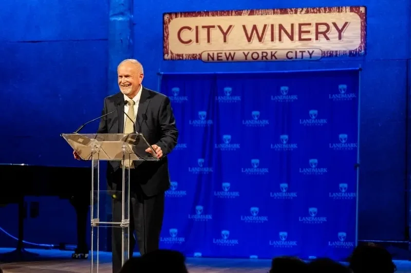 President James Dlugos standing on stage the gala with City Winery, New York City above a step and repeat.