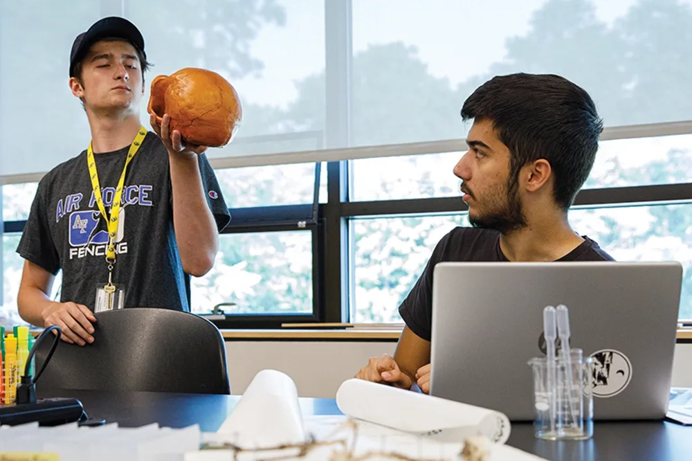 Two students in a lab observing a model of a skull.
