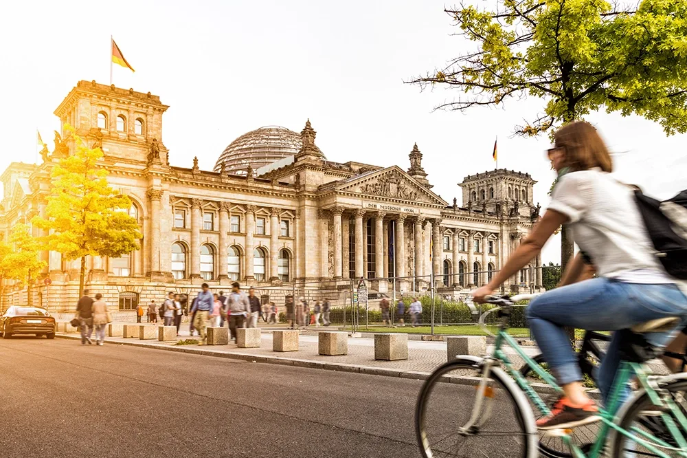 A woman riding a bicycle in Reichstag Germany.