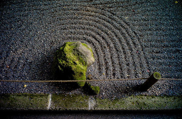 Semicircular lines drawn in gravel around moss-covered stone