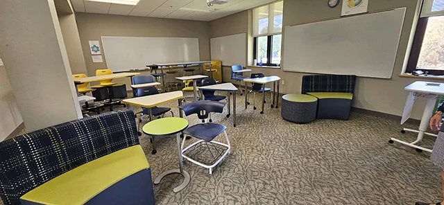 Colorful lime green and dark blue furniture in a classroom with tan floors.