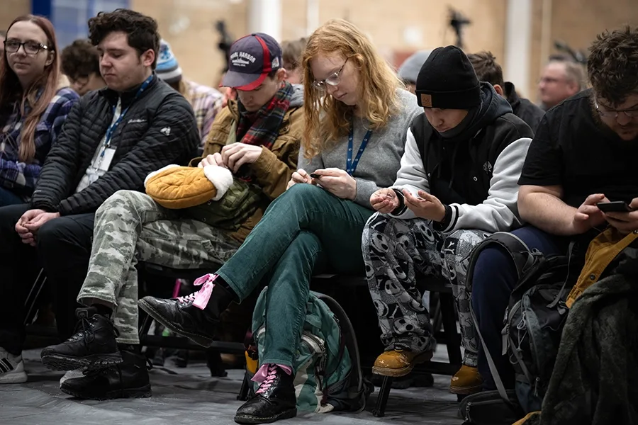 Students sitting in the front row of the convocation audience. Some of the students are looking at their Landmark coins.